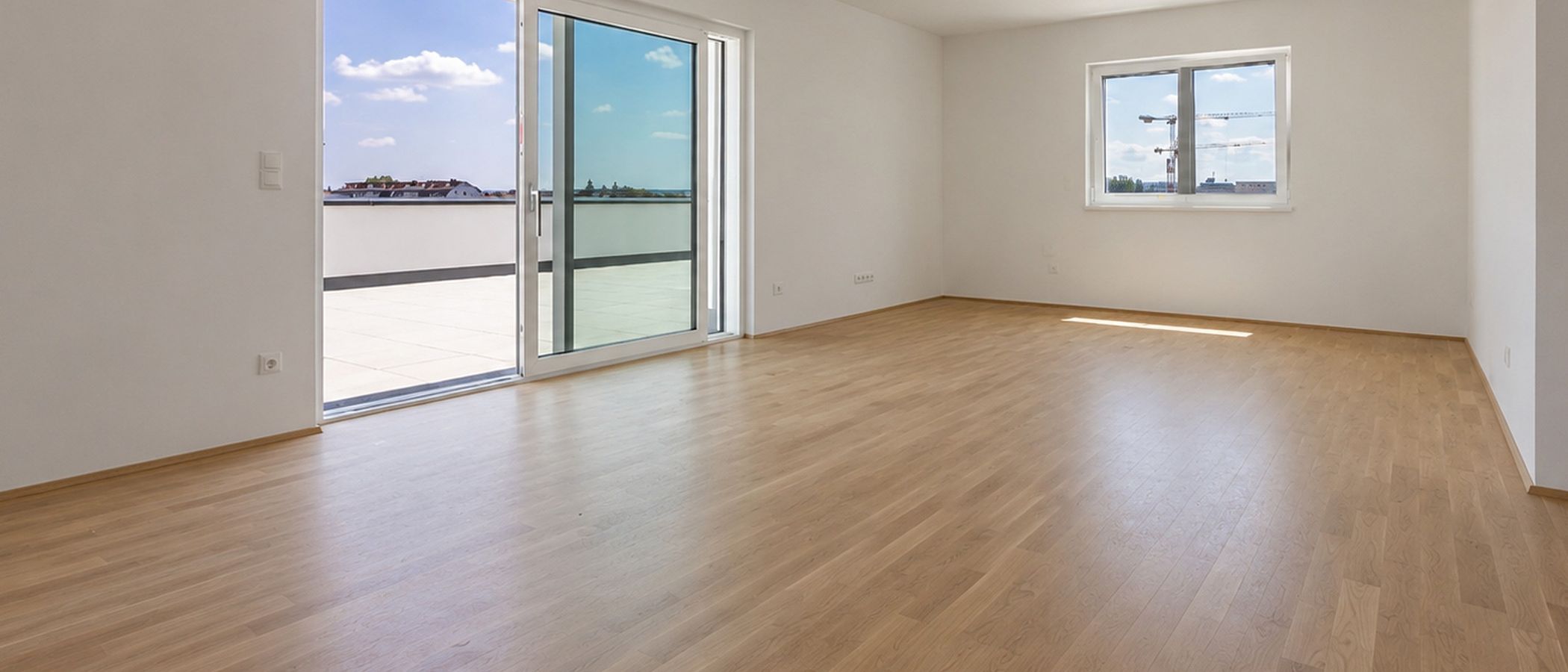 Helle, leere Wohnung mit Holzboden und Zugang zur Dachterrasse